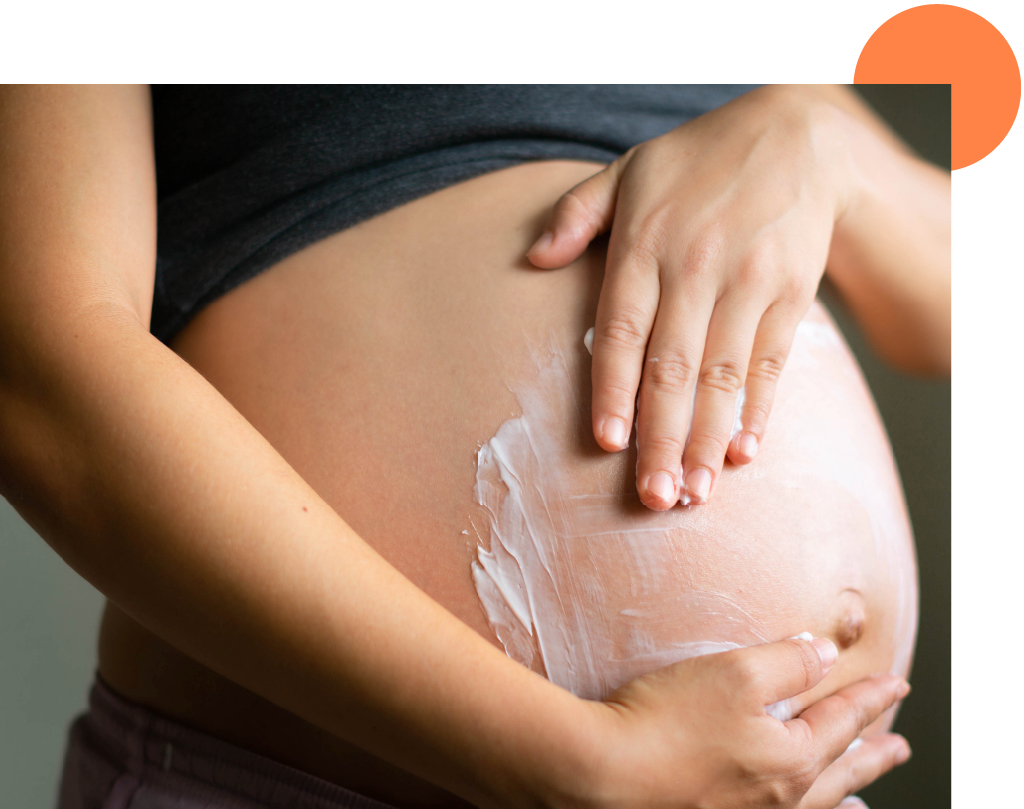 application de crème sur le ventre d'une femme enceinte