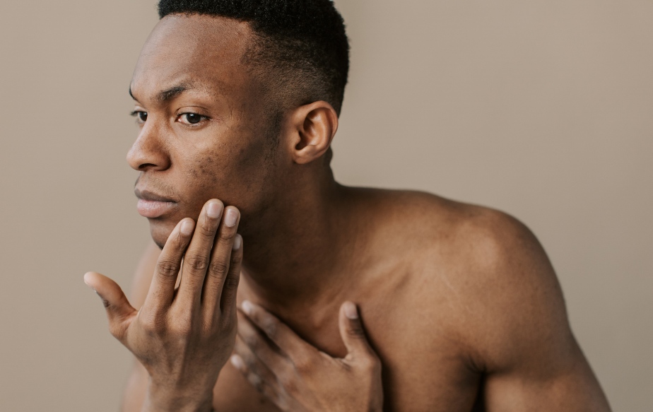Un homme noir qui fait sa routine beauté avec des produits adaptés à sa peau