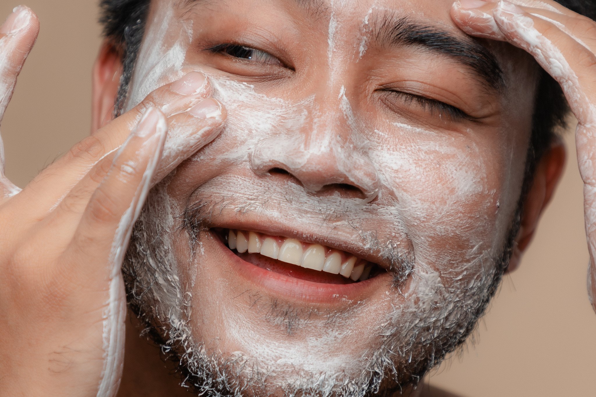 Un homme asiatique qui applique un nettoyant visage spécialement conçu pour les hommes