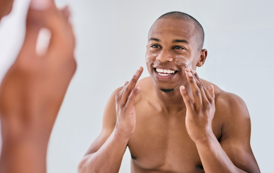 Un homme qui se met de la crème à base d'acide hyaluronique et un sérum à base de Vitamine C
