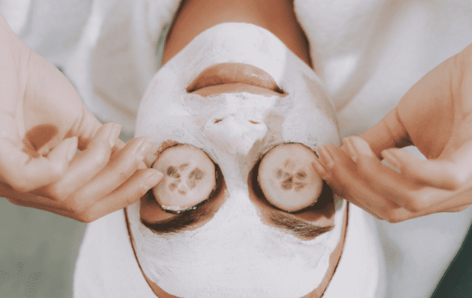 Une femme qui fait un masque visage avec des tranches de concombre sur les yeux pour enlever ses cernes